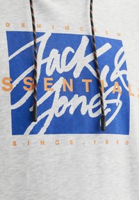 Sudadera gris con un gráfico rectangular azul que presenta texto en blanco y naranja. Los cordones negros y naranjas aportan contraste. Tejido de mezcla de algodón.