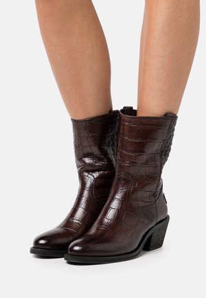 Brown leather ankle boots with a glossy croc-embossed finish, a high shaft, and a low block heel. Side zipper for easy wear.