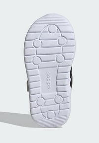 Biele tenisky so silikónovou podrážkou s horizontálnymi drážkami a kruhovými trakčnými bodmi. Názov značky "adidas" razený blízko päty.