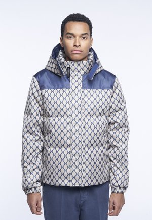Giacca imbottita color crema con motivo geometrico blu navy. Presenta un colletto alto, una chiusura con zip sul davanti e polsini elastici per una vestibilità aderente.