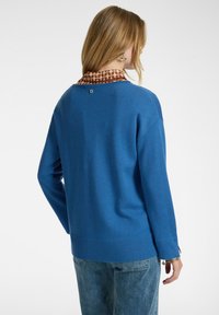 Suéter de punto azul con un corte relajado, ribete acanalado y un cuello de patrón marrón en contraste. Textura suave con un diseño sencillo.