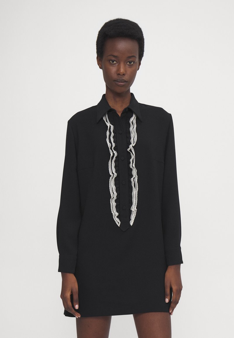 Rochie neagră cu butonieră, având un volan de dantelă albă pe față, mâneci lungi și un guler clasic. Țesătură netedă, ușoară.