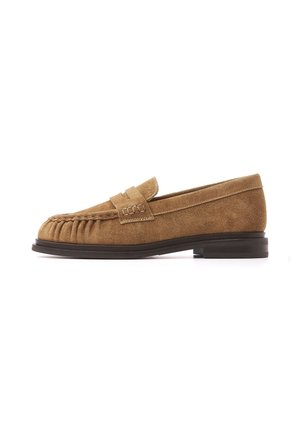 Brun ruskindslipper med sort sål, mokkasynsyning på tæen og en stroplignende detalje på oversiden.