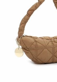 Sac à main marron matelassé avec une forme courbée, une texture rembourrée et une poignée en tissu. Doté d'une étiquette dorée et d'une fermeture éclair.