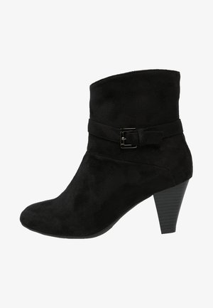 Stivale alla caviglia in suede nero con punta rotonda, dettaglio fibbia laterale e tacco affusolato. Presenta una texture liscia e un design elegante.