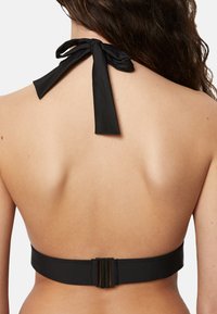 Musta halterneck bikinitop, jossa on nauhakiinnitys kaulassa ja leveä vaalean metallikannellinen nauha takana. Sileä kankaan rakenne.