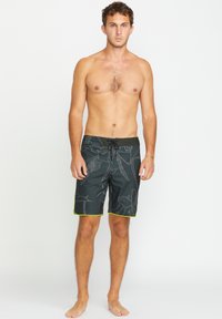 Costumi da bagno neri con un motivo di foglie grigio, dotati di un elastico in vita e dettagli in verde neon. Realizzati in materiale leggero e ad asciugatura rapida.