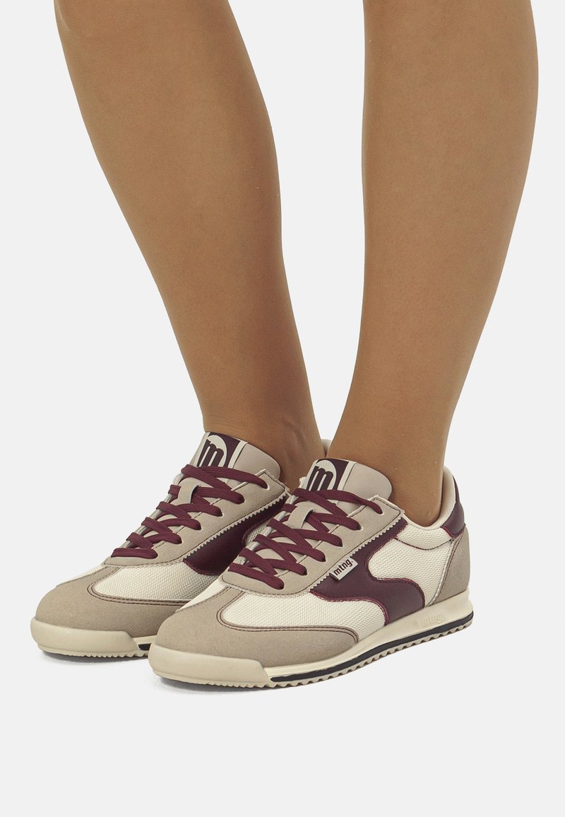 Zapatillas deportivas en beige y burdeos con materiales de malla y gamuza. Cuentan con cordones, un acento estampado y una suela texturizada.