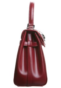 Dark red leather handbag shown from the side with a top handle and a small attached tag on a chain.