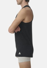 Camiseta deportiva sin mangas de color negro con un diseño ajustado, hecha de tela elástica. Presenta un logo de tres rayas blancas en el dobladillo.
