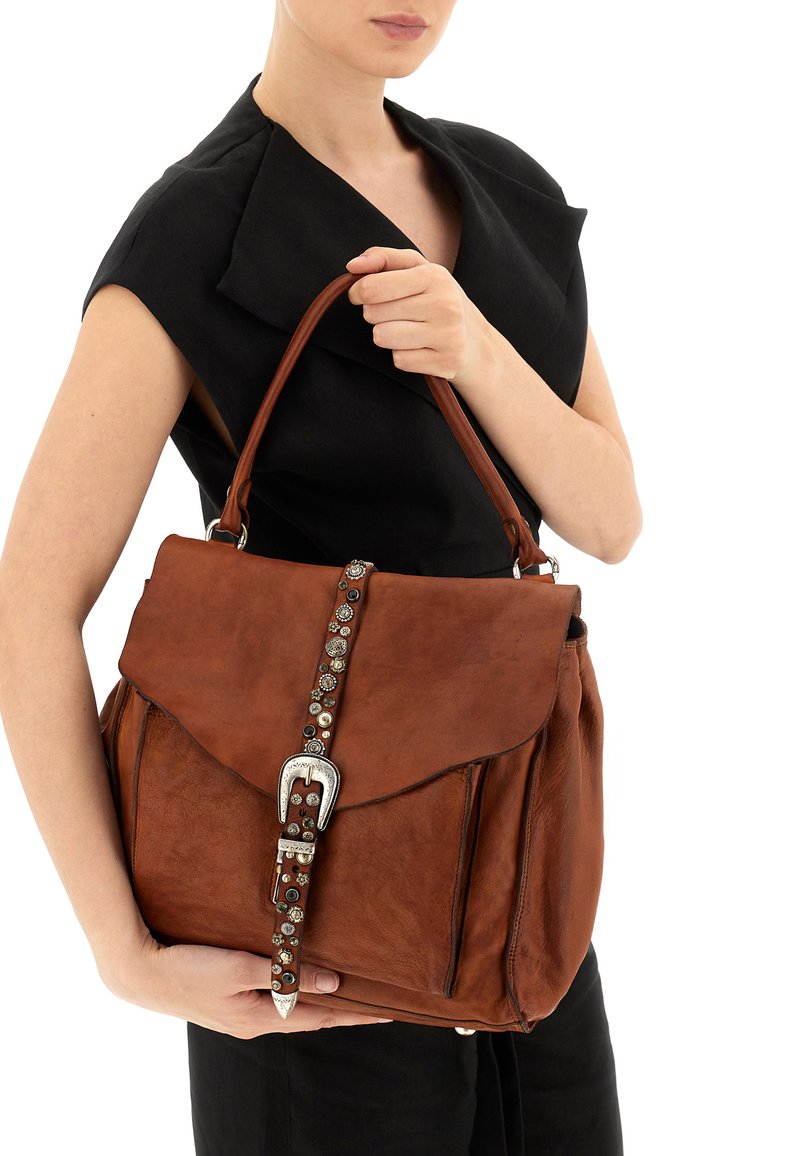 Borsa in pelle marrone con patta e fibbia decorativa. Presenta dettagli metallici e una forma strutturata, con un manico singolo superiore.