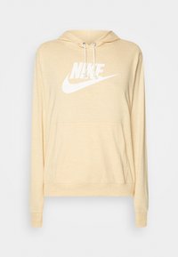 Světle žlutá mikina s kapucí vyrobená z měkké tkaniny, s přední klokankou, stahovací kapucí a velkým bílým logem Nike na hrudi.