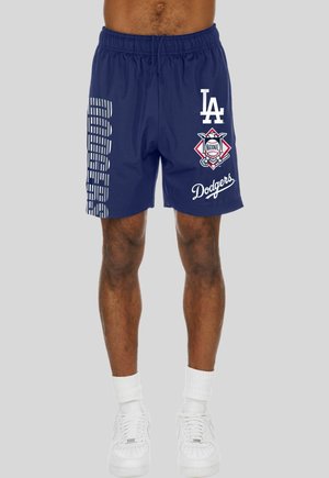 Marineblaue Shorts mit Los Angeles Dodgers-Logos und "Dodgers"-Text, getragen von einer stehenden Person mit weißen Socken und Schuhen.