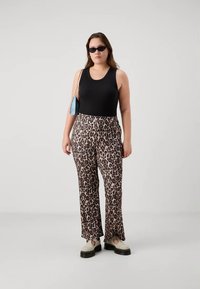 Μαύρο αμάνικο μπλουζάκι, παντελόνια με σχέδιο λεοπάρ και φαρδιά πόδια, και χοντρές λευκές παπούτσια. Τα αξεσουάρ περιλαμβάνουν μικρή μπλε τσάντα και μαύρα γυαλιά ηλίου.