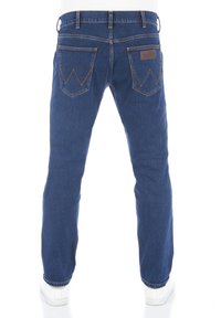 Jeans de mezclilla en azul oscuro con un diseño de pierna recta. Cuenta con dos bolsillos traseros con un patrón en zigzag y una etiqueta de cuero marrón en la cintura.