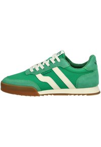 Sneaker sportive verdi caratterizzate da un mix di materiali lisci e testurizzati, strisce bianche e una suola in gomma marrone con un motivo a battistrada.