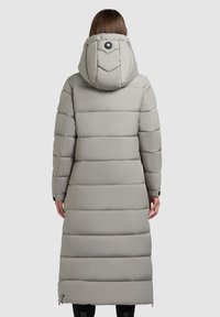 Lang, polstret grå frakke med hætte, der har detalje med sort knap og vandret syninger. Designet inkluderer sidelommer og en lige kant.