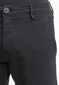 Svarta bomullsbyxor har knappstängning, flat front och sidofickor. Tyget har en mjuk yta med subtil lyster.