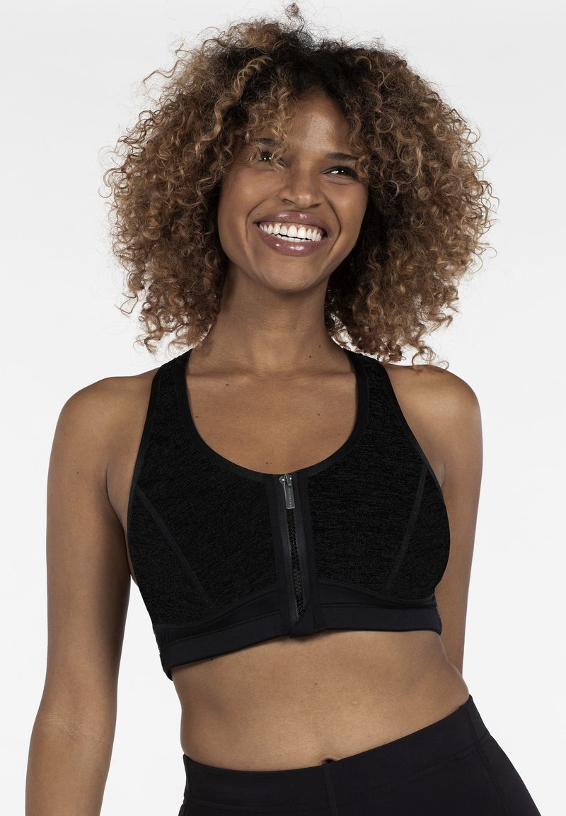 Black sports bra with a zip front, made of textured fabric. Features a racerback design and contrasting paneling along the sides.