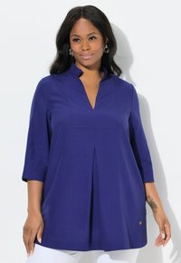Tunic con scollo a V e maniche a trequarti in tessuto blu navy solido, con una piega frontale e un bottone decorativo in tonalità oro all'orlo.