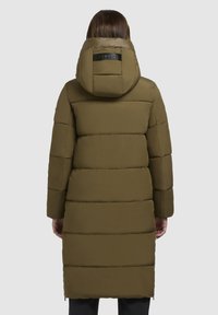 Olivovo zelená prešívaná bunda s horizontálnymi prešívanými sekciami, kapucňou a štítkom na chrbte. Texturovaný, vodoodolný materiál.