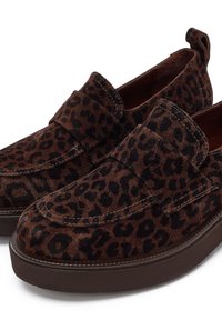 Mocassini in suede marrone con un motivo a stampa leopardata nera. Presentano una punta arrotondata e una robusta suola marrone. Accentuati da una larga fascetta sulla parte superiore.