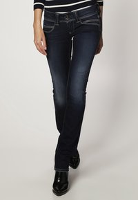 Mörkblå denimjeans med smal passform, med kontrasterande sömmar, framfickor, knappstängning och en subtil blekning.