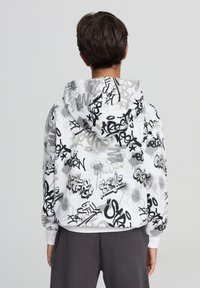 Felpa con cappuccio in tessuto bianco con motivi di graffiti neri e grigi, polsini elasticizzati e vestibilità comoda. Vista posteriore mostrata.