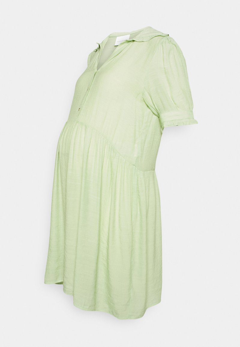 Vestido de maternidade verde-claro, até aos joelhos, em tecido leve com mangas curtas, frente com botões e uma saia fluida.