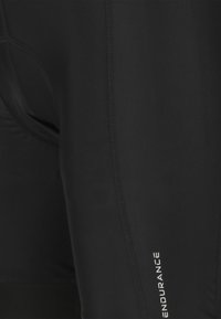 Nahaufnahme schwarzer sportlicher Shorts mit gepolstertem Innenfutter und vertikaler Naht mit dem Schriftzug "ENDURANCE" an der Seite.