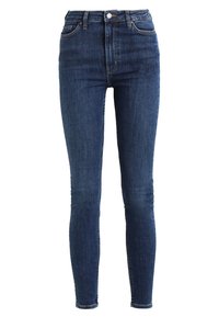 Jeans ajustados de denim azul oscuro, diseño de cintura alta, cinco bolsillos y un clásico cierre de botón y cremallera, con un ligero desgastado en la tela.