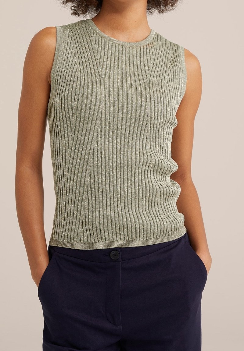 Ärm-lös ribbad topp i ljusgrön med en texturerad yta. Har en rund halsringning och en figurnära silhuett. Matchad med mörkblå byxor.