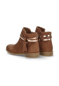 Botas de tobillo marrones con una textura suave, suelas planas, acentos metálicos y detalles de borlas. Cierre de cremallera en la parte posterior para facilitar el uso.