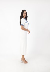 Weißes Rippkleid mit Denim-Kragen und kurzen Ärmeln, schlanker Schnitt und mittellanger Design, kombiniert mit durchsichtigen Absätzen.