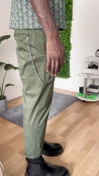 Green cotton trousers with side zipper pocket, connected by a silver chain. Black ankle boots with a thick sole complete the outfit.