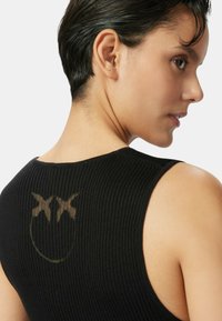 Top sin mangas negro de canalé con un diseño de cara sonriente descolorido en el centro y un escote bajo en la espalda. Corte ajustado, textura suave y diseño sin mangas.