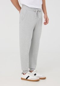 Pantaloni sportivi grigio chiaro realizzati in tessuto misto cotone, con vita elasticizzata, coulisse, tasche laterali e polsini alla caviglia affusolati.