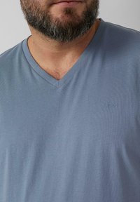 T-shirt z dekoltem w serek, krótki rękaw w jasnoniebieskim materiale o gładkiej fakturze; posiada małe logo s.Oliver na piersi.