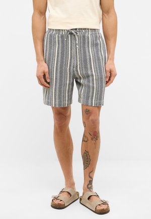 Stripede shorts i marineblå og cremefarvet vævet stof. Har en elastisk talje med snørre og sidelommer. Bæres sammen med beige sandaler.