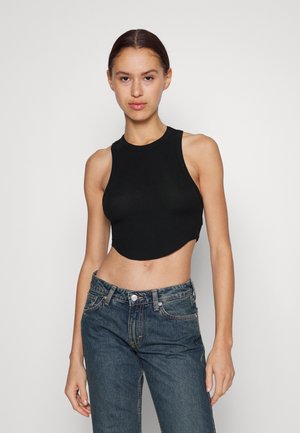 Μαύρο ριμπ crop τοπ με στρογγυλή λαιμόκοψη και χωρίς μανίκια, σε συνδυασμό με ψηλόμεσα μπλε τζιν. Λείος υφασμάτινος χαρακτήρας και εφαρμοστή γραμμή.