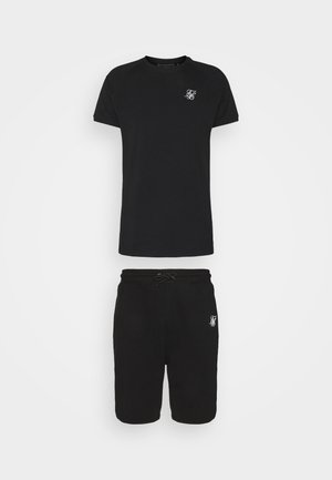 Schwarzes Kurzarm-T-Shirt und passende Shorts mit weißem stilisiertem Logo auf Brust und Oberschenkel, dargestellt vor einfarbigem Hintergrund.