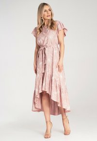 Różowa sukienka o krótkich falbaniastych rękawach, w kwiatowy wzór, z paskiem w talii i asymetrycznym dołem. Wykonana z lekkiego materiału.