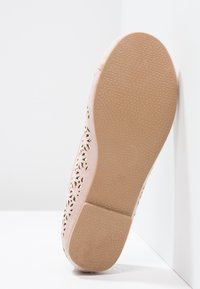 Světle růžová bota s perforovaným květinovým vzorem a texturovanou gumovou podrážkou. Podrážka má plochý tvar a velikostní štítek "30".