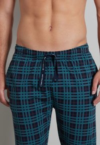 Men's pajama pants featuring a blue and dark patterned check design. Made from soft fabric with an elastic waist and drawstring closure.