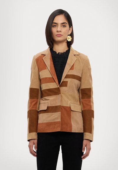 Patchwork blazer i tan og brun lavet af ruskind, med et klippet krave, to forlommer og kontrasterende rektangler i forskellige nuancer.