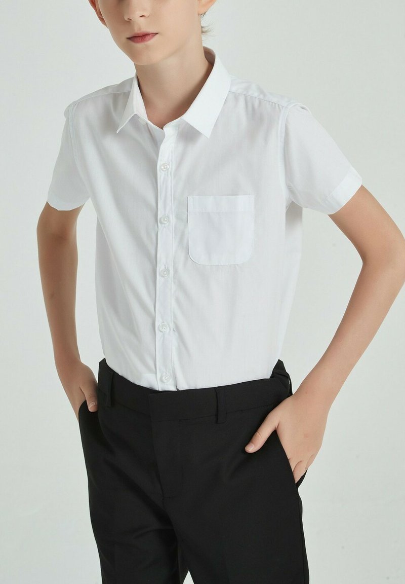 Chemise blanche à manches courtes avec patte de boutonnage et poche poitrine unique, assortie à un pantalon noir. Tissu lisse, coupe ajustée.