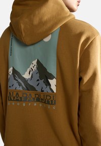 Sudadera con capucha en marrón cálido, que presenta un gráfico de montañas y un sol en azul, blanco y gris en la parte trasera, con una marca debajo.