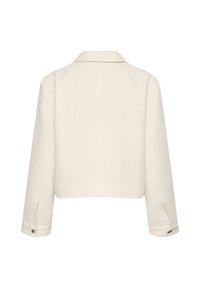 Kermanvärinen lyhytaikainen takki, jossa on teksturoitu kangas, lovettu kaulus ja napitetut hihat. Takana on puhdas ja minimalistinen muotoilu.