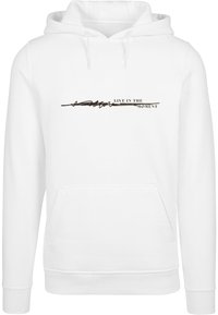 Weiße Kapuzenpullover mit frontaler Tasche, ausgestattet mit einem schwarzen Druckdesign, das "LEBE IM AUGENBLICK" sagt. Weicher Stoff und elastische Bündchen.