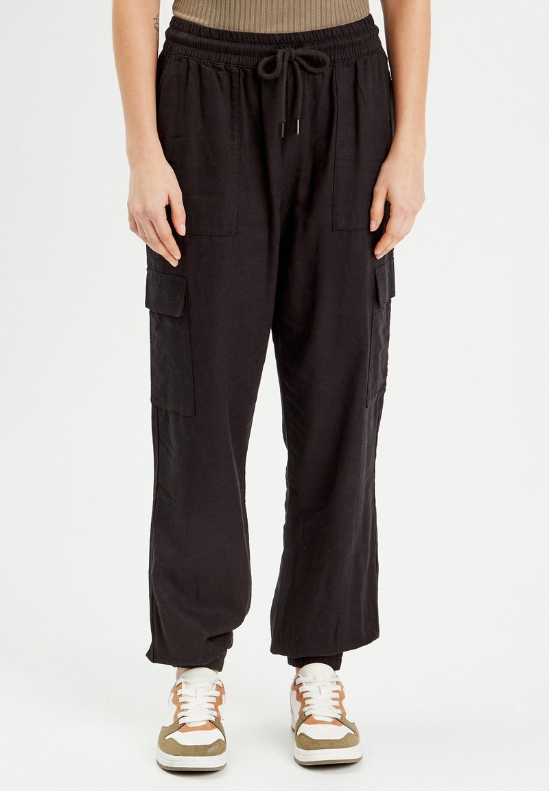 Pantalons cargo en lin noir avec une taille élastique, fermeture à cordon, deux poches latérales et une coupe fuselée au niveau des chevilles.